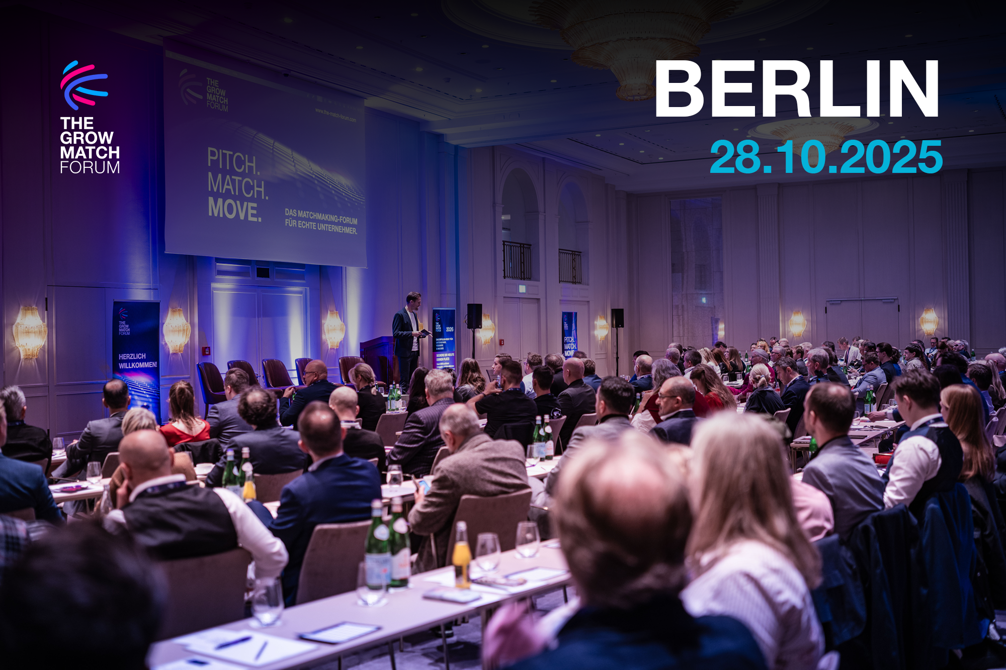 Smiling woman with curly hair at a formal dinner table, wearing a smartwatch. Background shows people in conversation, wine glasses, and bottled water.
